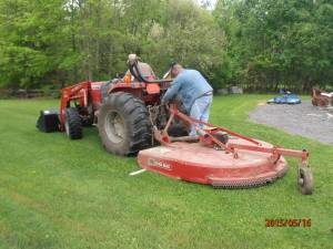 They are removing the brush hog to attach the rototiller.